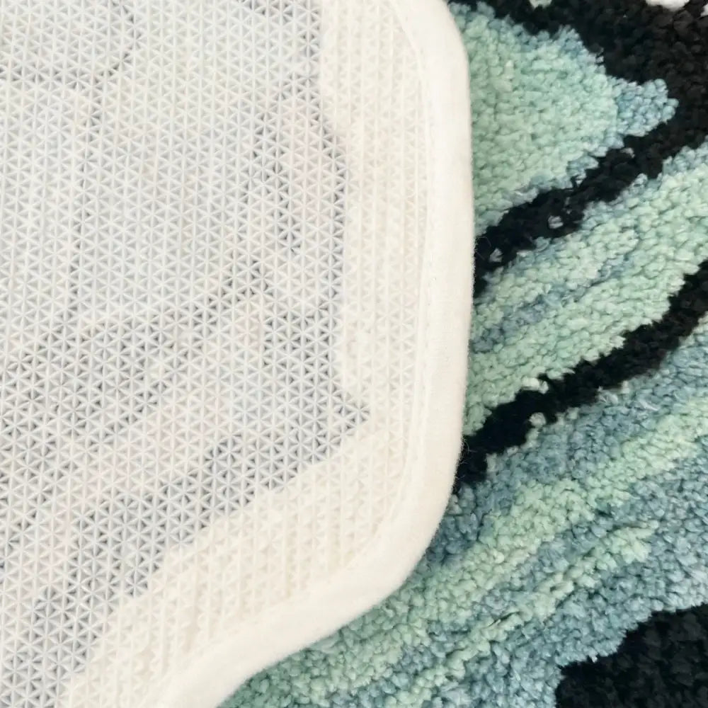 Sac à linge en filet blanc avec un fond de tapis à motif noir et turquoise.