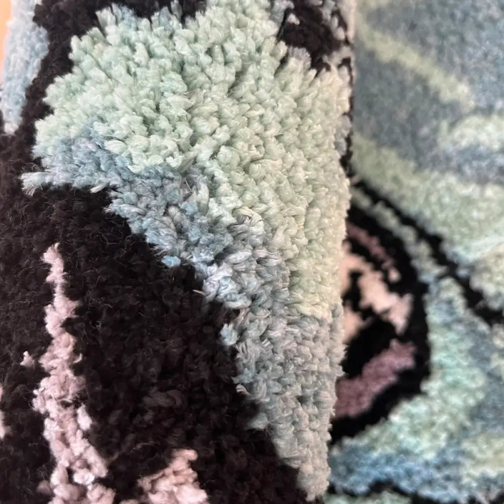 Tapis de bain texturé vert clair avec des accents noir et rose, probablement fabriqué en microfibre ou en matériau moelleux.