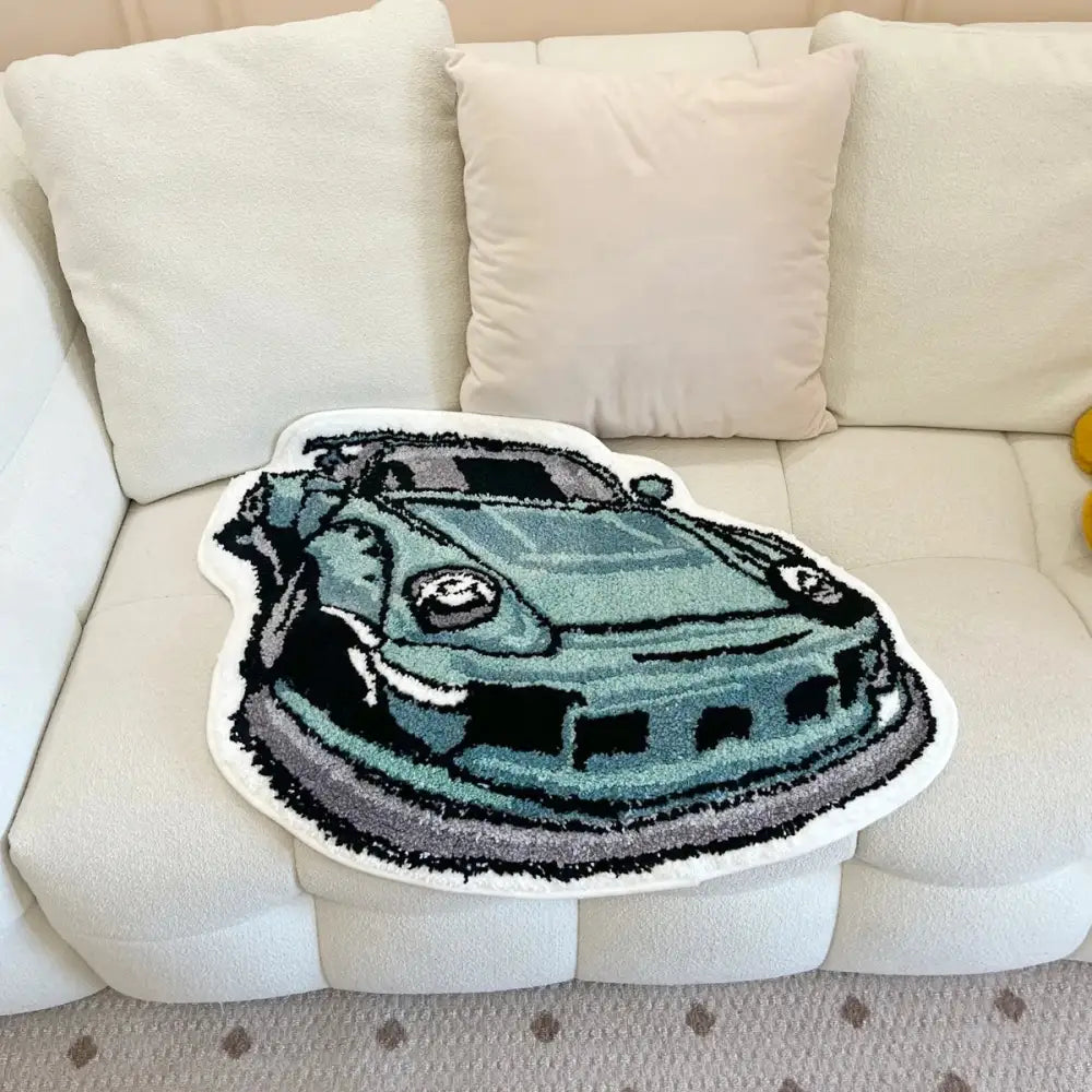 Coussin de lancer en forme de voiture verte avec surpiqûres blanches et une surface texturée.