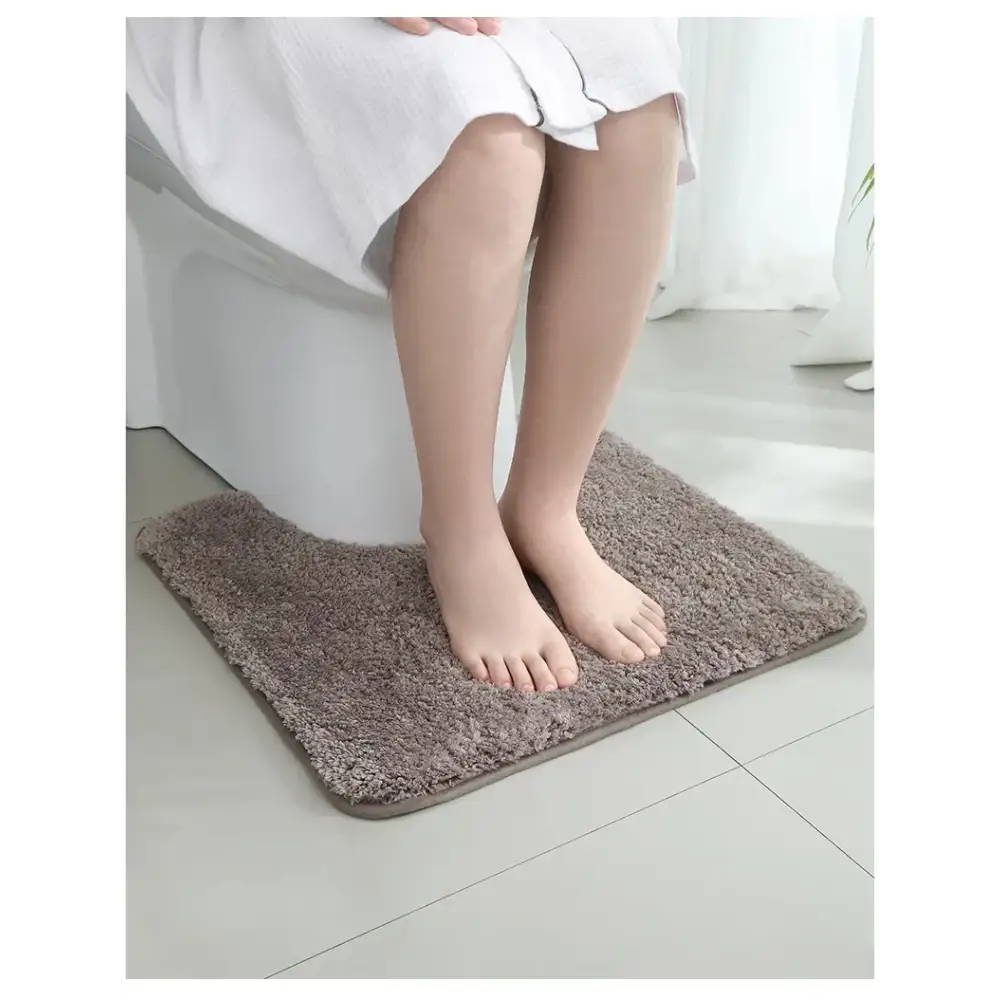 Tapis wc taupe gris en peluche avec texture douce et bord légèrement surélevé pour salle de bain confortable