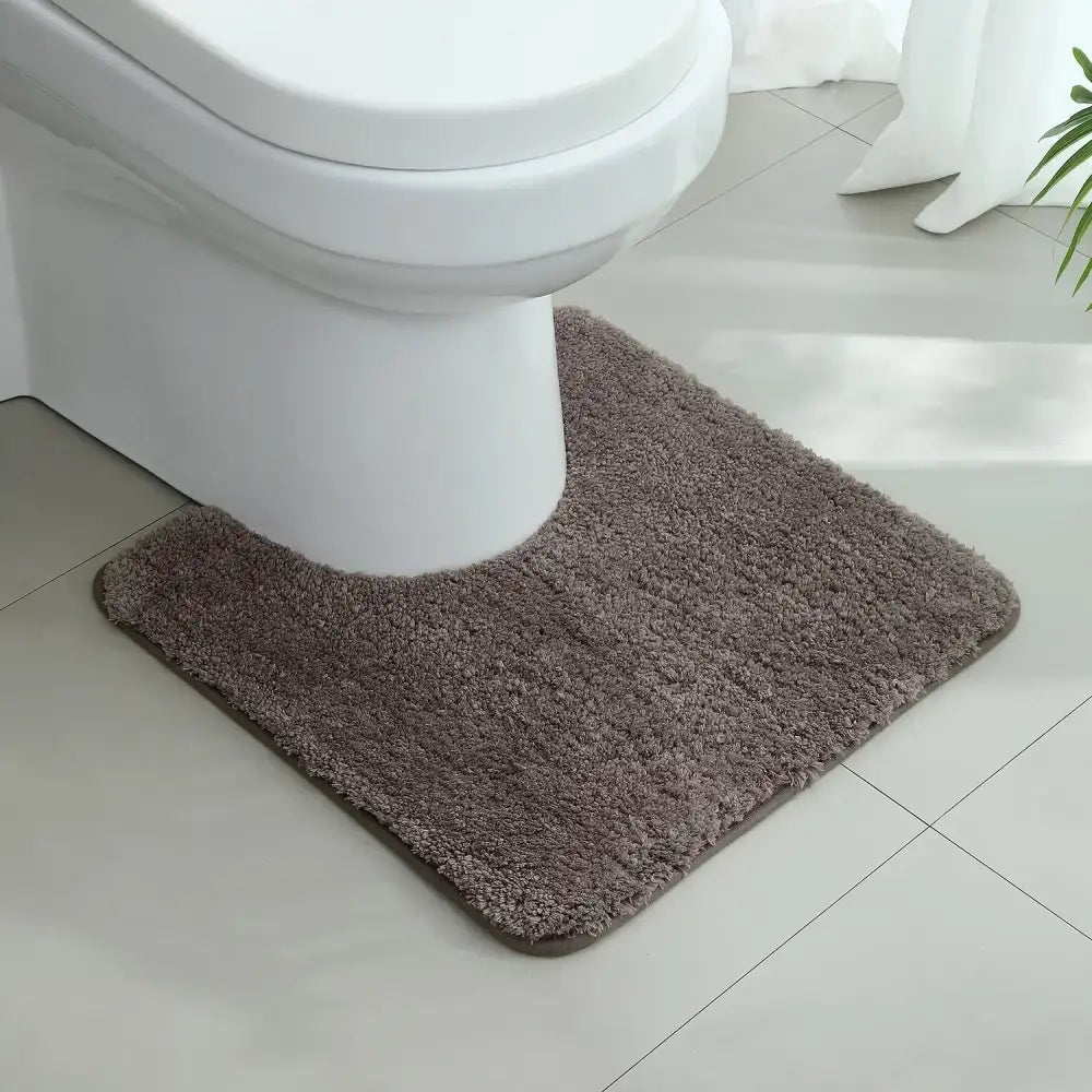 Tapis wc taupe en tissu pelucheux gris foncé avec texture douce et bord arrondi pour salle de bain confortable