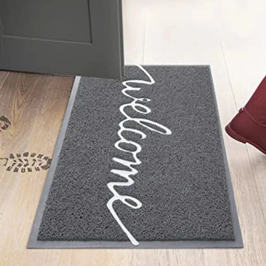 Paillasson de bienvenue avec script en cursive, fond gris et texte blanc.