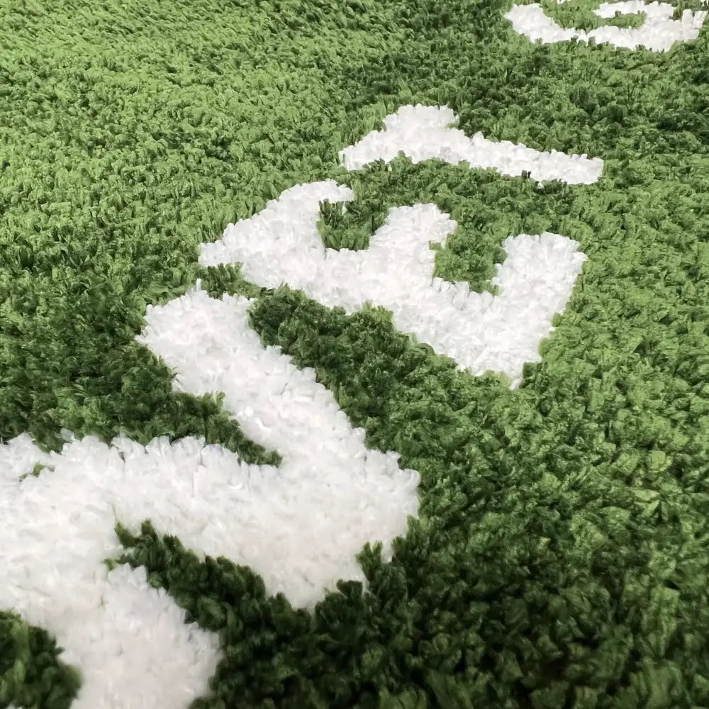 Tapis en peluche vert et blanc avec une surface texturée et ébouriffée.