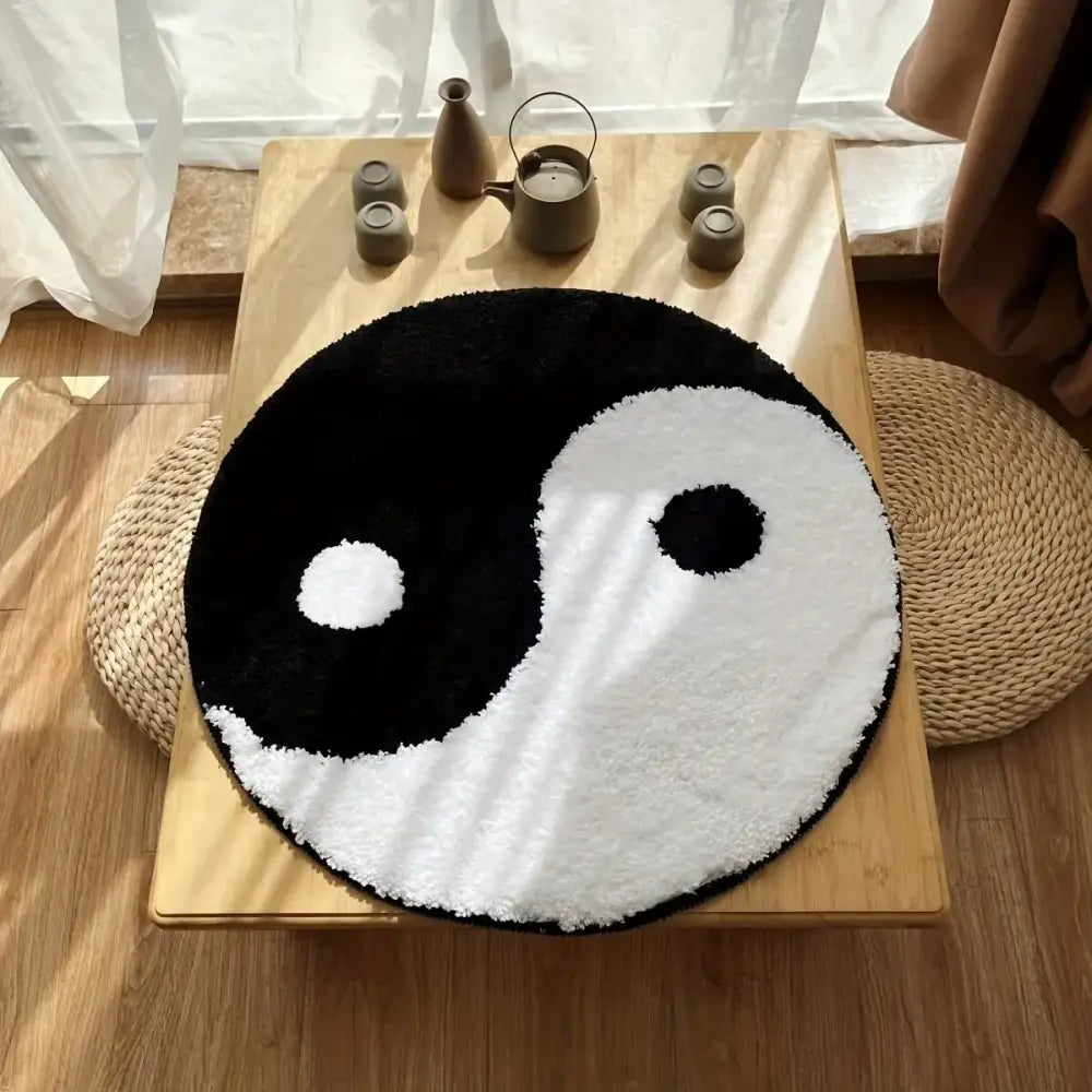 Tapis yin yang avec un design noir et blanc sur une table en bois.
